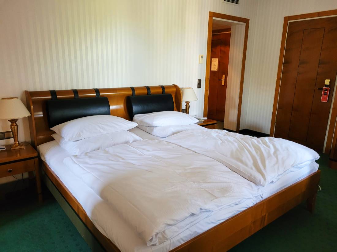 Doppelbett aus Holz, Türen und Nachttisch mit Lampe, grüner Teppich