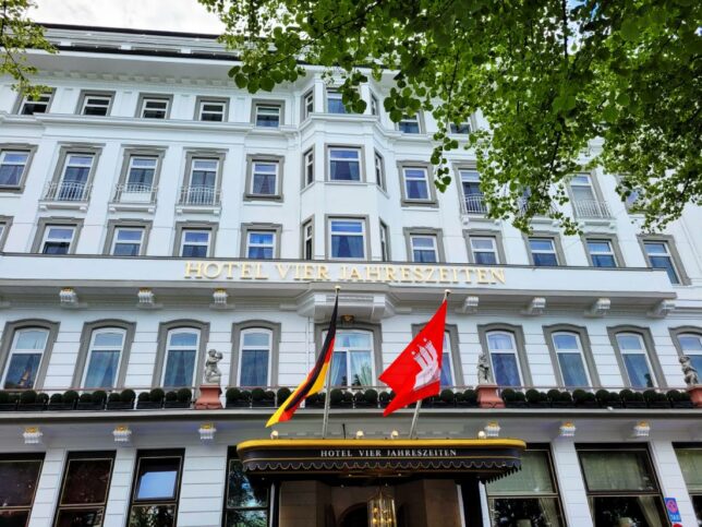 Weisse Aussenfassade mit zwei Flaggen und Eingang Hotel Vier Jahreszeiten Hamburg