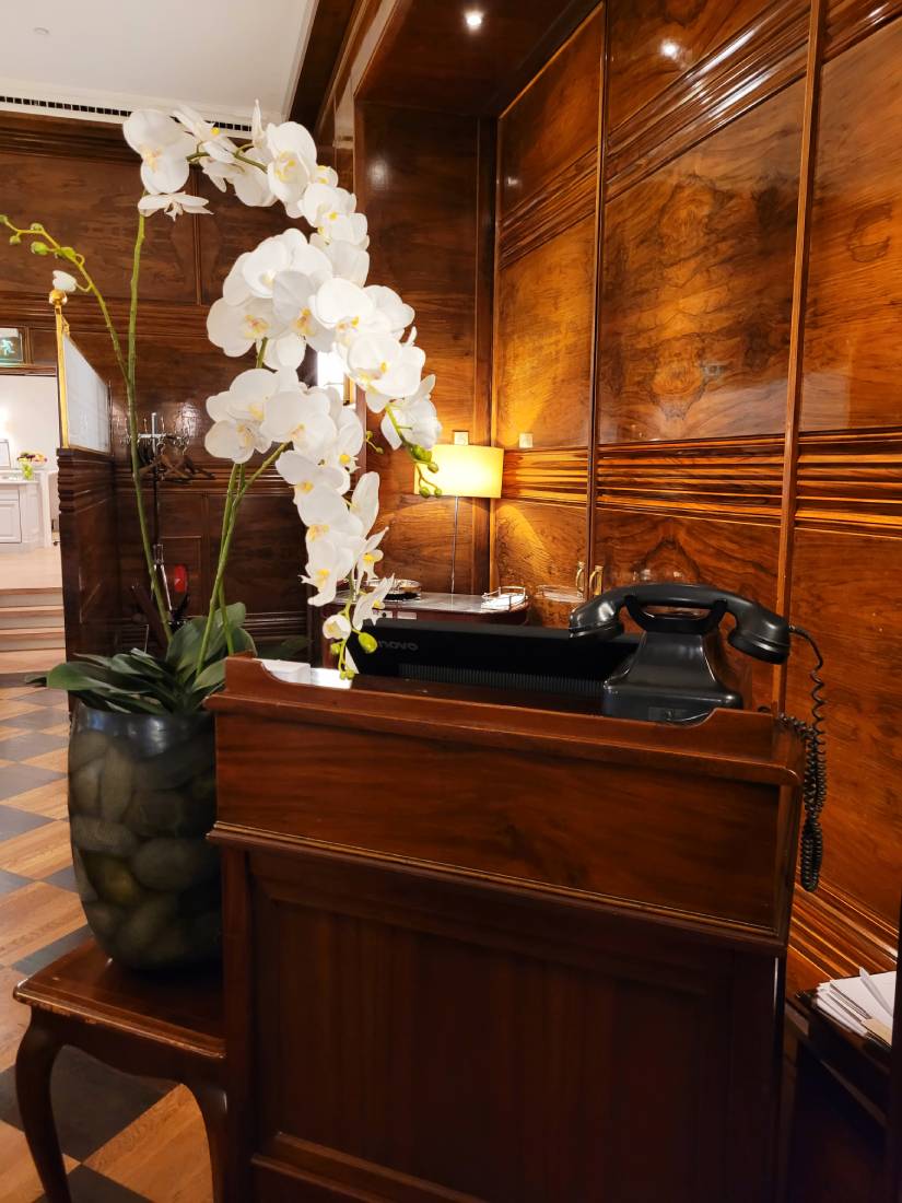 Concierge Desk, altmodisches schwarzes Telefon, weisse Orchidee im Hotel Vier Jahreszeiten Hamburg